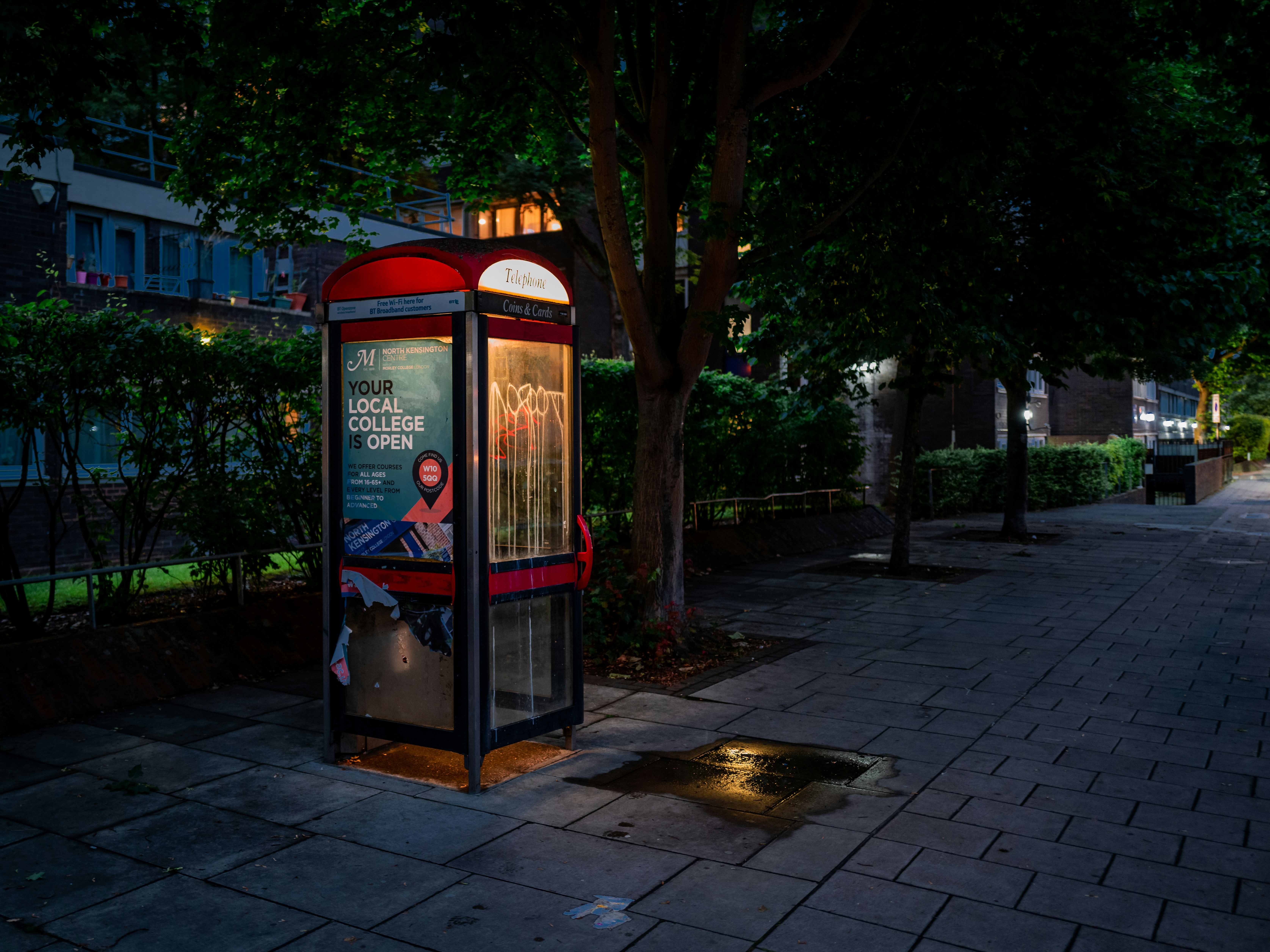 red and black telephone booth near green trees during daytime